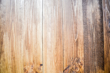 Vertical surface made of light brown stained wooden planks, featuring prominent grain and knots. The rightmost plank is slightly darker. Natural texture or background