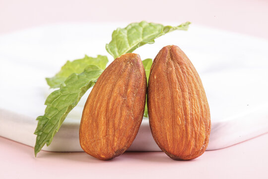 Whole Almonds with Fresh Green Leaves on Pink Background