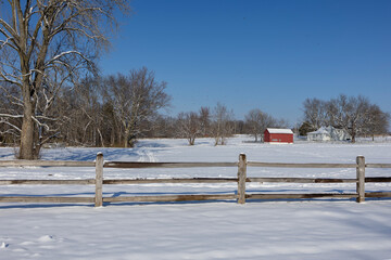 winter landscape with a fence and red barn