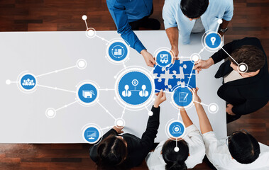 Aerial view of a diverse team working together around a table with digital connection icons, symbolizing collaboration and problem solving in a modern office environment. Amity