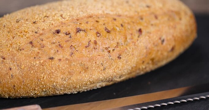 a soft loaf of bread on black slate, a freshly baked soft loaf of rye bread lies on the table