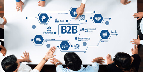 A conceptual image of business strategy featuring multiple hands on a table with B2B icons...