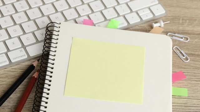 Woman putting sticky note, other stationery and computer keyboard at wooden table, closeup