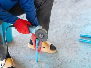 A construction Worker Cutting Blue PVC Pipe with Electric Angle.