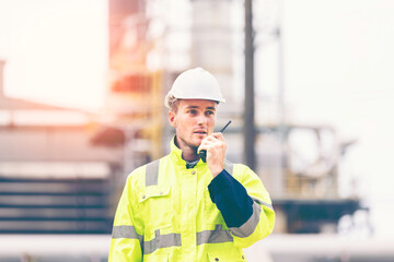  Engineers workers with tablet in a refinery - oil processing equipment and machinery, Industry zone gas petrochemical. Factory oil storage tank and pipeline. Workers in the refinery construction.