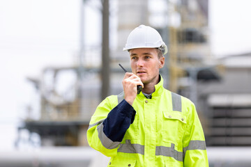  Engineers workers with tablet in a refinery - oil processing equipment and machinery, Industry zone gas petrochemical. Factory oil storage tank and pipeline. Workers in the refinery construction.