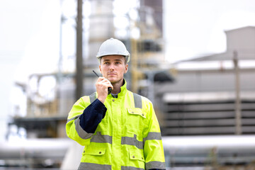 Engineers workers with tablet in a refinery - oil processing equipment and machinery, Industry zone gas petrochemical. Factory oil storage tank and pipeline. Workers in the refinery construction.