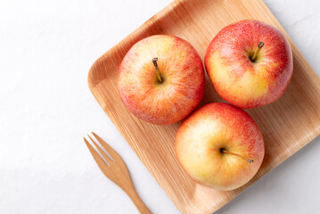 Red apple fruit (Gala apple) in natural plate with wooden fork on white background, Top view