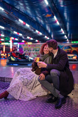 Happy couple enjoying fun night at amusement park fair