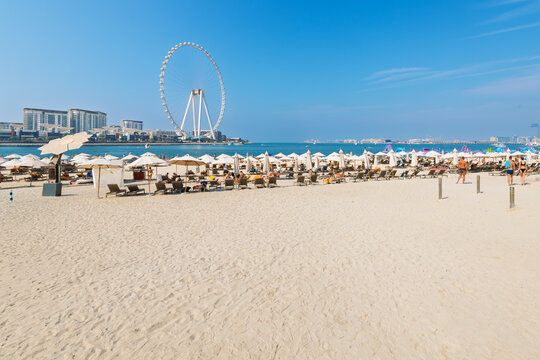 Visitors enjoy the sandy Jumeirah Beach, or JBR beach along the Persian Gulf with the Ain Dubai Ferris wheel behind, in Dubai, United Arab Emirates.