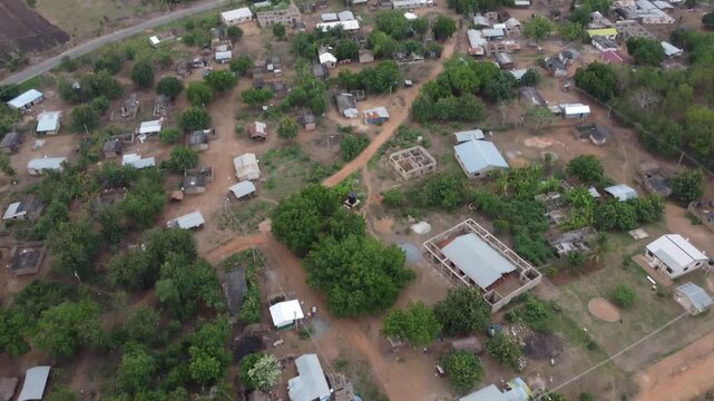 Aerial drone footage of Ghana, Africa, serene lake surrounded by mountains. Traditional boats across the water near a local village, with views near the Right to Dream Football Academy