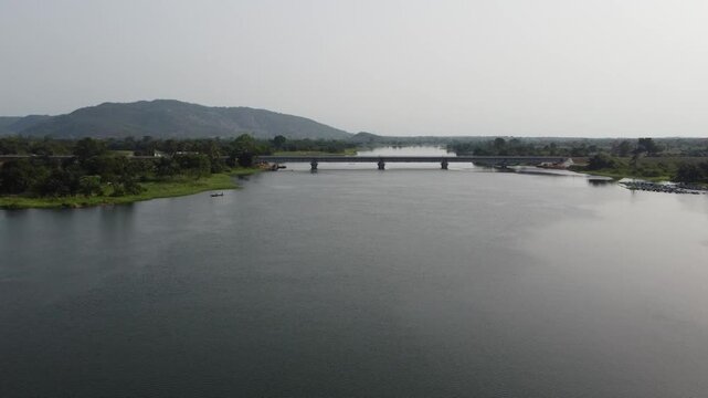 Aerial drone footage of Ghana, Africa, serene lake surrounded by mountains. Traditional boats across the water near a local village, with views near the Right to Dream Football Academy