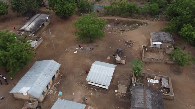 Aerial drone footage of Ghana, Africa, serene lake surrounded by mountains. Traditional boats across the water near a local village, with views near the Right to Dream Football Academy