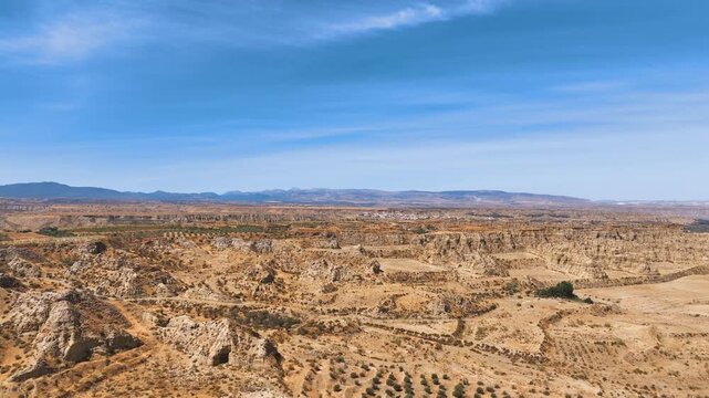 Low aerial into the wild rugged eroded badlands outside of Guadix Granada Spain