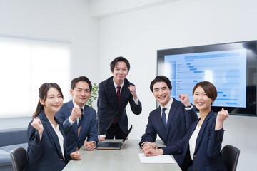 オフィスで会議するビジネスマン男女のガッツポーズ