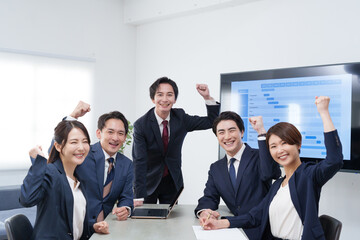 オフィスで会議するビジネスマン男女のガッツポーズ
