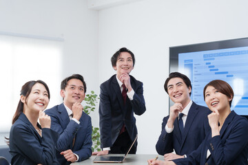 オフィスで会議するビジネスマン男女が考える