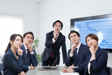 オフィスで会議するビジネスマン男女が考える