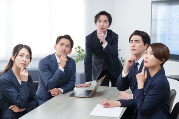 オフィスで会議するビジネスマン男女が考える