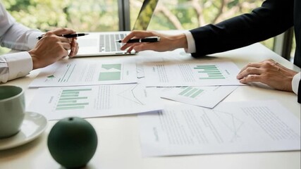 Business colleagues collaborating on financial data analysis with laptop and reports in a modern office meeting - Powered by Adobe
