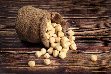 Roasted Hazelnuts in Burlap Sack on Rustic Wood Background