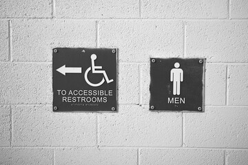 Blue restroom signs for men and accessible facilities mounted on a wall in Corona, California, highlighting ADA compliance and public access.