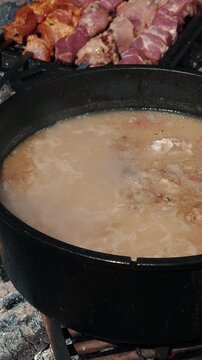 Cauldron with kulish prepared on fire. Picnic time. Barbecue meat frying on fire. Vertical video