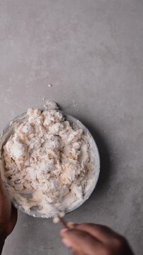 Overhead view of scallion pancake dough being poured on a grey countertop, top view of cong you bing dough being mixed, process of making scallion pancakes