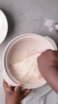 overhead view of focaccia dough being mixed in a claypot, top view of a high hydration focaccia bread dough in a donabe, process of making high hydration focaccia