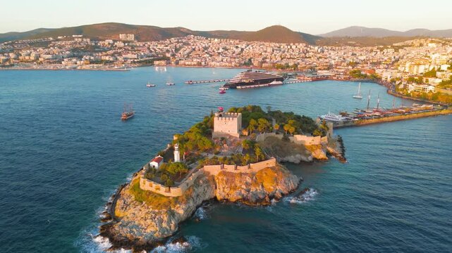 Kusadasi, Turkey. Aerial view of the historic Pigeon Island Fortress at sunset. The shot captures the Pirate Castle built by Barbarossa, glowing in the evening light.. Aerial View, Departure of the c