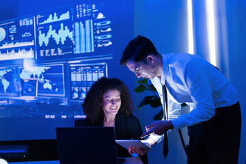Business professionals collaborating in a modern office with data visualizations displayed on large screens