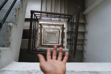 A hand reaches over a stairwell, creating strong visual rhythm through geometric repetition, depth, and a moment of hesitation.