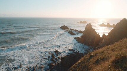 Sunset over rocky coastline with ocean waves crashing and sunlight shining on water