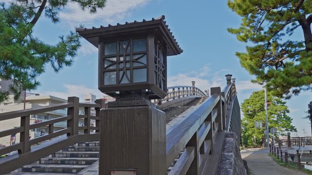 Close-up detail of a traditional Japanese wooden lantern and bridge railing at the Hyakudai Bridge on the Soka Matsubara path.