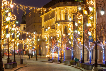 Festive Christmas light decorations on streets in Warsaw, Poland during night in winter © Kavalenkava