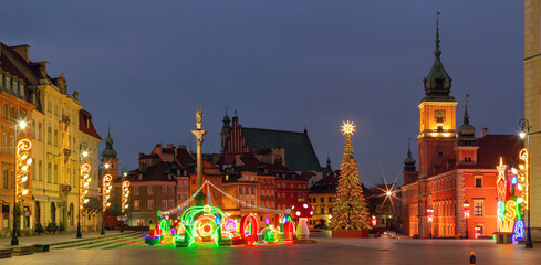 Illuminated Christmas decorations and tree at main square in Warsaw, Poland during winter evening