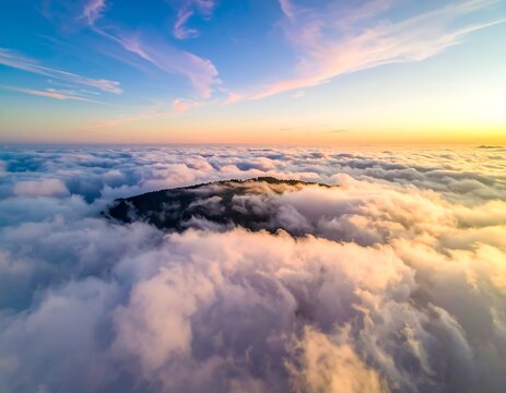 Aerial view of a mountain peak emerging from fluffy clouds at dawn - Powered by Adobe