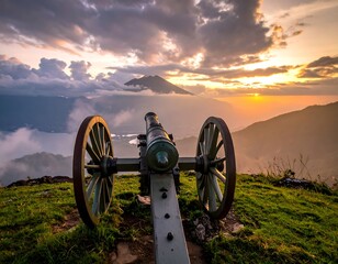 Cannon on a hilltop overlooking a valley and a majestic mountain range during a vibrant sunset
