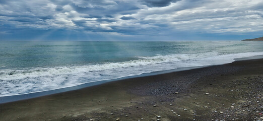Beach scene with waves under cloudy sky over coastal seashore horizon