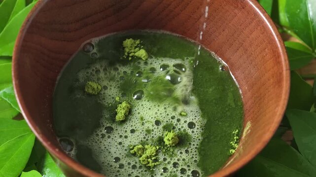 Process making matcha green tea. Mixing matcha tea with whisk in wooden bowl. Healthy matcha drinks	