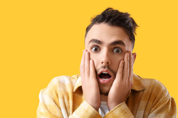 Young man having panic attack on yellow background, closeup