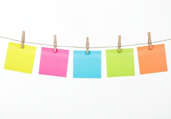 Multicolored sticky notes hanging on string isolated on white background, creative planning and workflow concept for business organization, teamwork, and visual communication.
