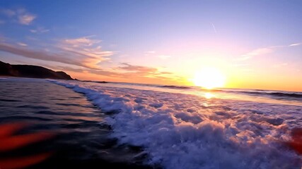 A breathtaking golden hour sunset over the vast ocean with gentle waves reflecting the vibrant hues of orange pink and purple across the tranquil water creating a serene and picturesque coastal lands.