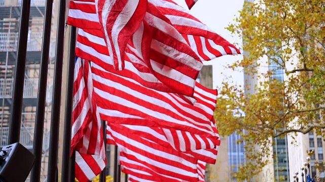 Closeup of waving US flags NYC. A detailed closeup captures US flags waving strongly near Rockefeller Center buildings.
