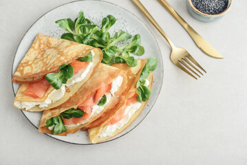 Crepes or thin pancakes with lightly salted salmon, soft cheese and cornsalad