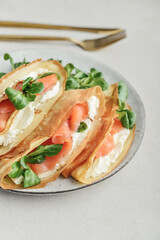 Crepes or thin pancakes with lightly salted salmon, soft cheese and cornsalad