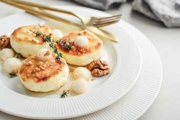 cottage cheese pancakes, syrniki, curd fritters served with pear balls, walnut and honey
