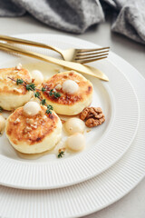 cottage cheese pancakes, syrniki, curd fritters served with pear balls, walnut and honey