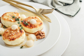 cottage cheese pancakes, syrniki, curd fritters served with pear balls, walnut and honey