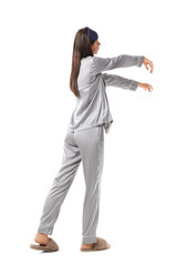 Female sleepwalker in pajamas on white background, back view